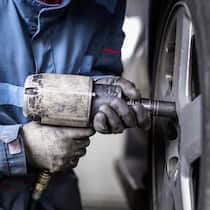 Enorme Preisunterschiede bei Garagen Ein Automechaniker wechselt einen Reifen an einem Auto.