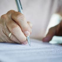 Worauf es beim Testament ankommt Nahaufnahme einer älteren Frauenhand, die ein Dokument unterschreibt. Was in einem Testament stehen muss.