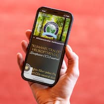 Streit um «umweltfreundlichen Helikopterflug» Eine Person hält ein Smartphone mit der Klima-Werbung der Firma Elite Flights in der Hand.