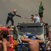 «Danke für euren Kampf» – ein Funken Hoffnung im Waldbrandsommer Ein Feuerwehrmann reicht einem freiwilligen Helfer eine Atemschutzmaske, während sie am 29. Juli 2026 einen Waldbrand in Lanton, östlich der Bucht von Arcachon und westlich von Bordeaux, bekämpfen.