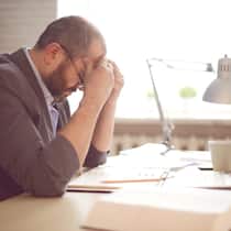 Das ist zu tun, wenn Lieferanten Sie betreiben Geschäftsmann sitzt an Schreibtisch und hat den Kopf aufgestützt.