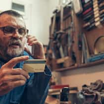 Immer mehr Telefonbetrug – das können Sie tun Senior man in the workshop holding credit card and talking by phone