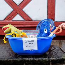 Dürfen wir das an die Strasse stellen? Eine blaue Plastikbox an der Strasse ist gefüllt mit Plüschtieren, Spielsachen und Kinderbüchern, die mit dem Verweis «Gratis zum Mitnehmen» versehen sind.