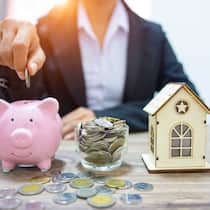 Wohin mit dem PK-Guthaben? Eine Frau wirft eine Münze in ein Sparschwein. Daneben steht ein Glas voll mit Münzen und rechts davon ein kleines Spielzeughaus. Wer seine Stelle verliert und nicht sofort eine neue antritt, muss sein Guthaben aus der Pensionskasse irgendwo unterbringen. Eine Möglichkeit wäre, das Geld für Wohneigentum vorzubeziehen.