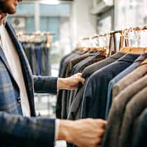 Gutschrift oder Bargeld? Ein Ladenverkäufer schaut sich die Anzüge an, die aufgereiht an einer Kleiderstange hängen.