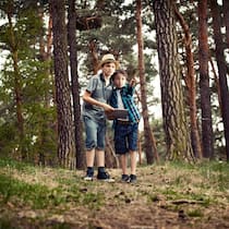 Jetzt aber nichts wie raus! Zwei Jungen stehen im Wald und halten ein Tablet in der Hand.