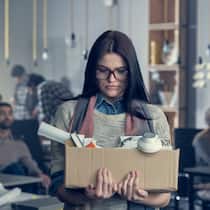 So kündigen Sie richtig Junge Frau, der kündigt wurde. Sie hält eine Schachtel mit ihren Arbeitsutensilien in der Hand.