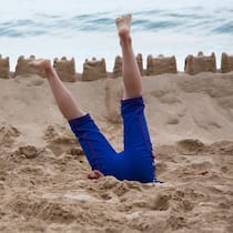 Müssen wir uns für die Reise ins Ausland extra versichern lassen? Eine Person steckt kopfvoran im Sand fest – Wer während der Ferien im Ausland erkrankt oder verunfallt, braucht in der Regel keine zusätzliche Reiseversicherung. Diese lohnt sich nur, falls man sich speziell absichern will oder bei Ländern mit hohen Behandlungskosten