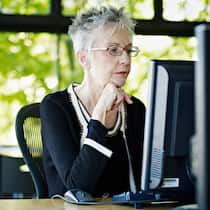 Können Frühpensionierte Arbeitslosengeld beziehen? Eine ältere Frau arbeitet im Büro am Computer.