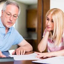 Ein Beistand nach Mass Eine Frau und ein Mann sitzen zusammen am Tisch und studieren Unterlagen.