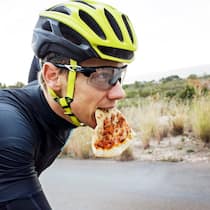 Das sind die häufigsten Ernährungsfehler bei Hobbysportlern Ein Velofahrer mit Helm und Brille hat ein Stück Pizza im Mund. Die wichtigsten Fragen zu Ernährung und Sport.