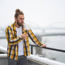 Können Vermieter das Qualmen gänzlich verbieten? Ein junger Mann raucht an einem verschneiten Wintertag auf dem Balkon eine Zigarette. Müssen sich bei einer Mietwohnung auch Besucher an ein vertragliches Raucherverbot halten?