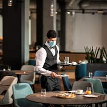 Muss ich den Gutschein akzeptieren? Ein Angestellter eines Hotels räumt alleine einen Frühstückstisch ab.