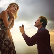 Was gilt rechtlich in der Ehe? Ein Mann macht einer Frau einen romantischen Hochzeitsantrag an einem Strand.