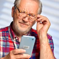 7 Übungen gegen eckige Augen Ein älterer Mann schaut angestrengt auf sein Handy.