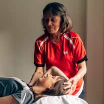 Die mit den Händen sieht Die blinde Physiotherapeutin Rita Dütsch behandelt eine junge Patientin am Nacken.