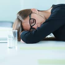 Der Büroschlaf ist der gesündeste Eine Frau macht im Büro ein Nickerchen.