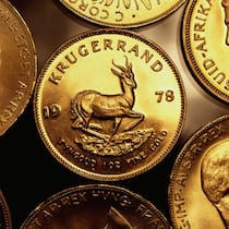 In Gold investieren – wie geht es am besten? Mehrere Krügerrand Goldmünzen liegen auf einer Oberfläche