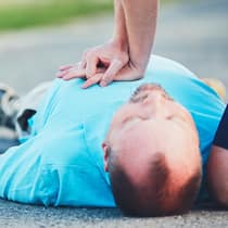 So reagieren Sie richtig bei einem Herzinfarkt Ein Mann mit einem Herznotfall liegt auf der Strasse und wird reanimiert.