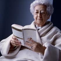 Kann ich Mutter zwingen, ins Heim zu ziehen? Eine ältere Dame liest ein Buch.