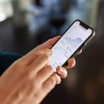 Soll ich kurz vor dem Börsengang zuschlagen? Eine Person sieht sich auf einem Smartphone einen Aktienkurs an.