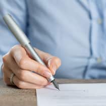 Vollmacht unterschreiben – darauf sollten Sie achten Eine Frau unterschreibt ein Formular für eine Vollmacht. Welche Arten von Vollmacht es gibt und welche Folgen sie haben.