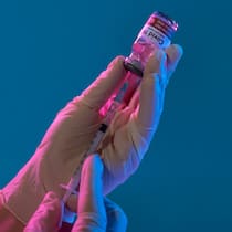 Schwer geschädigt – wen interessierts? Bild einer medizinischen Fachperson, die eine Dosis eines Corona-Impfstoffs in einer Spritze aufzieht.