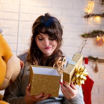 Vielen Dank für das Geschenk, aber ... Eine junge Frau öffnet ein verpacktes Weihnachtsgeschenk, schaut in die Box hinein und verzieht dabei die Mundwinkel. Wer zu Weihnachten etwas geschenkt bekommt, das nicht gefällt oder passt, kann das Präsent unter Umständen an den Händler zurückgeben oder es weiterverschenken.