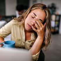 Was gilt bei der Arbeit? Eine Angestellte kämpft sichtlich mit ihrer Konzentration bei der Arbeit.