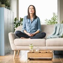 Rechte und Pflichten der Mieter Junge Frau sitzt mit überkreuzten Beinen auf dem Sofa in ihrer Wohnung.