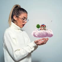 Rechtliche Fallen beim Wohnungskauf Eine junge Frau träumt von einem Haus und hält dieses in ihrer Vorstellung in den Händen