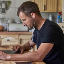 Mit positiver Einstellung zum Erfolg – so gehts Man working from home, sitting at kitchen table with cat, using laptop