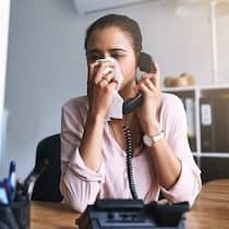 Zum Arzt, weils der Chef so will Eine junge Frau sitzt im Büro am Telefon und niesst, es ist Erkältungs- und Grippezeit. Ab wann brauche ich ein Arztzeugnis?
