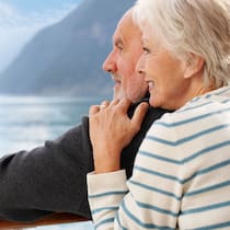 Rente oder Kapital – das ist hier die Frage Ein pensioniertes Ehepaar geniesst den Ruhestand und lässt den Blick über einen See schweifen.