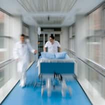 Teure Überraschung auf Spitalrechnung Arzt und Pflegefachkraft schieben Spitalbett durch Gang