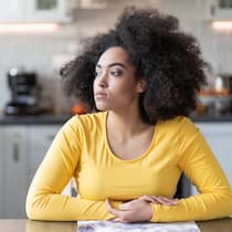 Schimmel in der Wohnung artet in Streit aus Eine junge Frau sitzt in ihrer Wohnung und schaut gedankenversunken um sich herum.