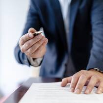 Diese Unterschrift wird sehr teuer Close-up of businessman in office presenting ballpen and contract