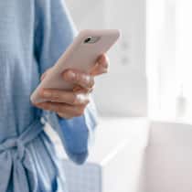 3 Tipps zur Selbstbegrenzung Eine Frau liest im Bad auf ihrem Smartphone Mails, während sie am Zähne putzen ist.