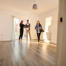 Reicht unser Geld für eine Wohnung? Ein junges Paar besichtigt eine Wohnung zusammen mit einer Immobilienmaklerin.