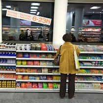 Wie Coop und Migros ihre Preise hoch halten Eine Frau steht vor einem Verkaufsregal mit Schokoriegeln in einem Coop-Pronto. Die Preise der beiden grössten Detailhändler Coop und Migros sind oftmals identisch. Schreiben sich die beiden Riesen bei den Preisen etwa ab?