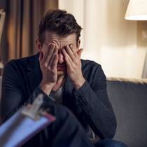 Wer kann mir durch die Krise helfen? Ein Psychotherapeut im Gespräch mit seinem Patienten, der das Gesicht in den Händen vergräbt.