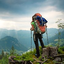 Unfall beim Wandern – wer haftet? Ein Wanderer in der Rückansicht schaut von einem Berg ins Tal. Wer haftet, wenn Wanderer verunfallen oder Schaden verursachen.