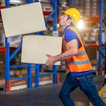 Zahlen Angestellte für ihre Fehler? Ein Mitarbeiter einer Lagerhalle gerät ins Stolpern. Dabei fällt eine von zwei Schachtel zu Boden, die der Mitarbeiter beim Umfallen nicht mehr festhalten kann.