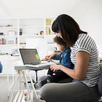 Alle Aufmerksamkeit beim Jüngsten Eine Mutter spielt mit ihrem jüngsten Kind während das ältere sich alleine beschäftigt