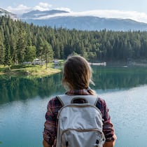 10 Tipps für nachhaltiges Reisen Junge Frau blickt auf Schweizer Bergsee und das Alpenpanorama