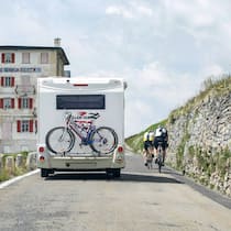 Im Ausland mieten, in der Schweiz fahren Ein Wohnmobil überholt auf der Passstrasse des Furka zwei Velofahrer.