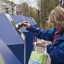 Die Recycling-Lüge Frau wirft in Zürich Altglas in den Recycling-Container