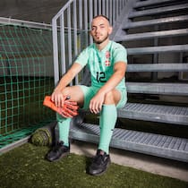 «Ich liebe die Goalie-Position» Patrick Allenbach sitzt im Fussballtenue auf einer Treppe in einer Sporthalle, offener Blick in die Kamera, Goalie-Handschuhe in der Hand