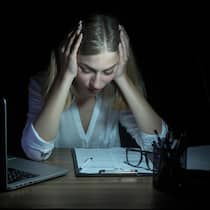 Immer Ärger mit dem Zeugnis Geschäftsfrau starrt in der Dunkelheit auf Unterlagen auf Tisch