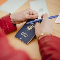 So werden ukrainische Angestellte in der Schweiz besteuert Frau hält ukrainischen Pass beim Ausfüllen der Registrierungsformulare im Bundesasylzentrum Zürich